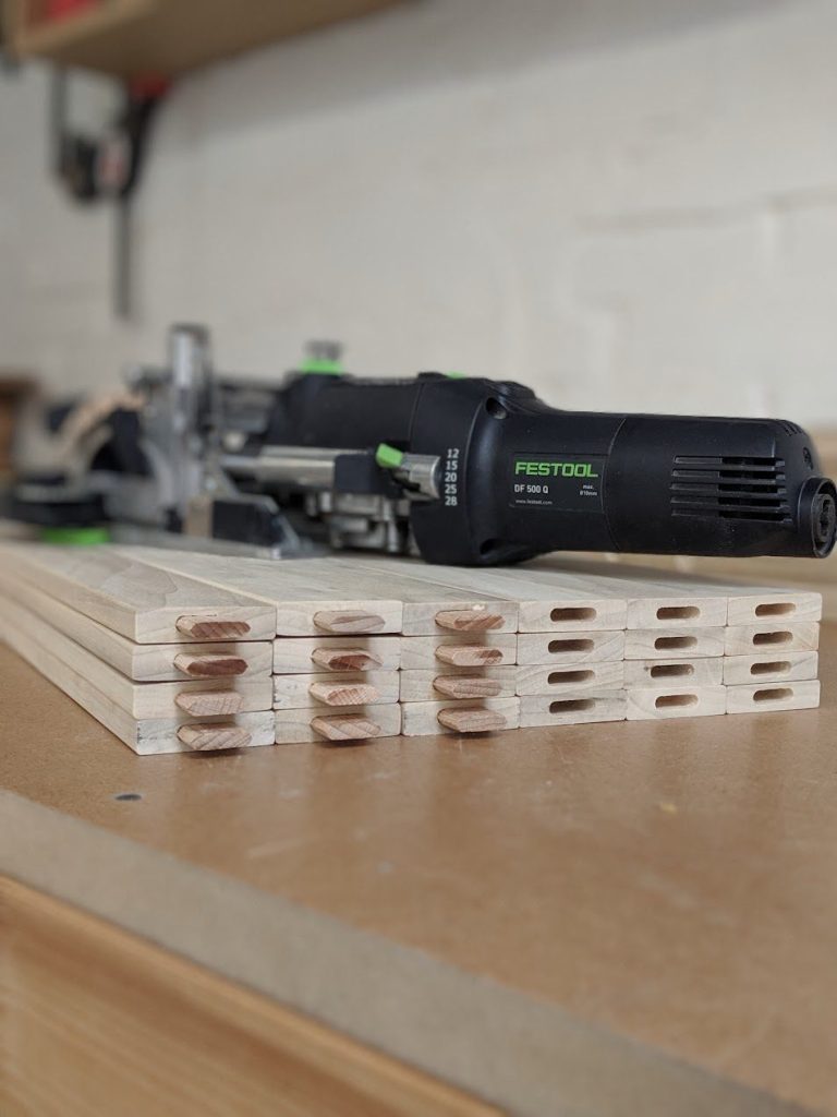 Festool Domino DF 500 Q joiner on a stack of rails, with dominoes fitted in the ends