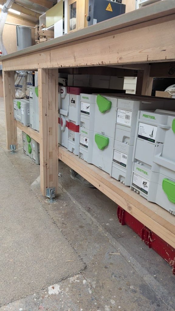 Festool Systainers stacked on the shelf under a workbench