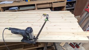Corded jigsaw cutting pine boards in a workshop, corded vs cordless power tools