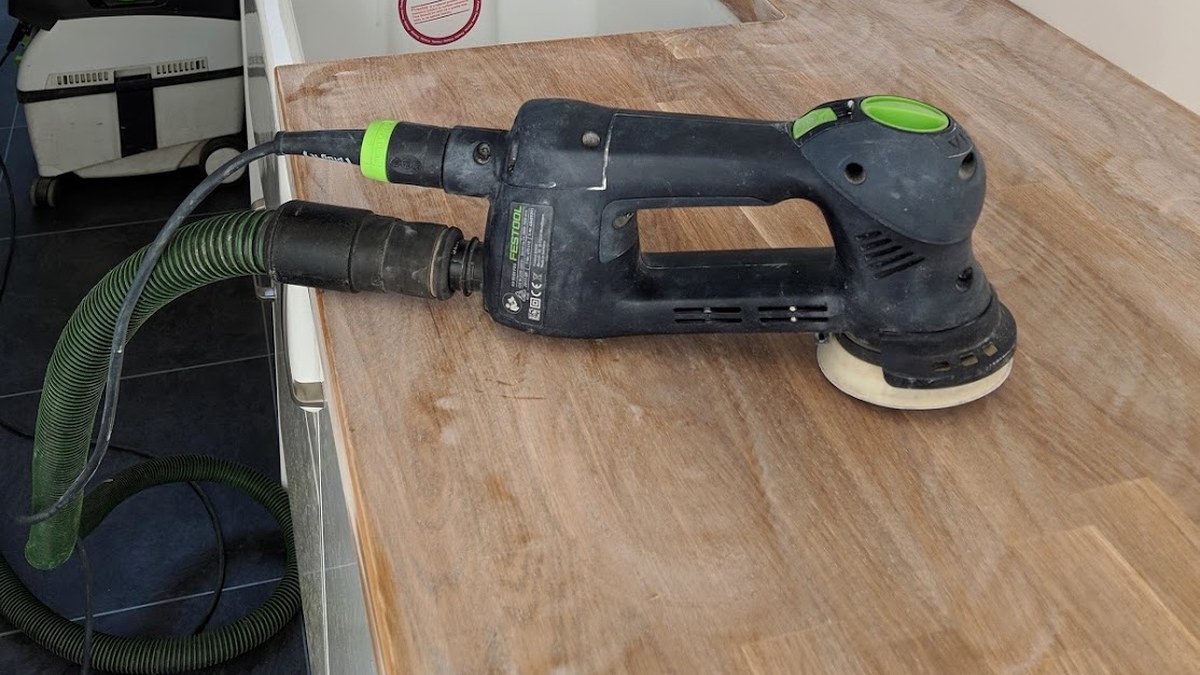Corded random orbital sander and dust extractor working on an oak worktop