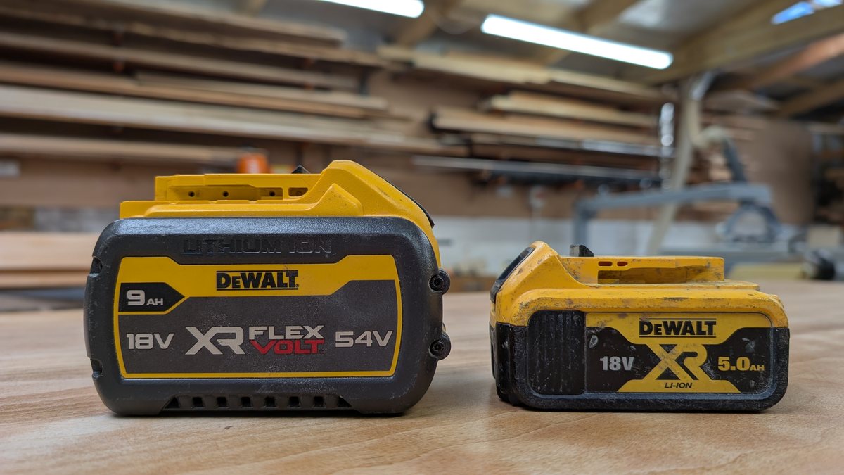 A DeWalt 9.0Ah FlexVolt pack beside a 5.0Ah XR pack on a workbench, showing the size difference