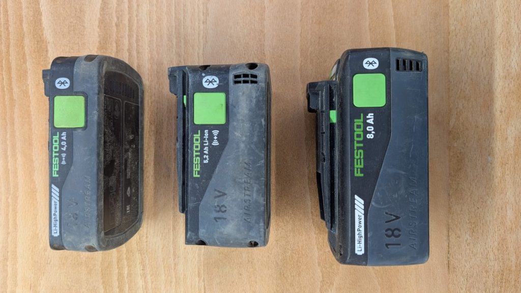Three Festool 18V battery packs of different capacities stood side by side on a workbench