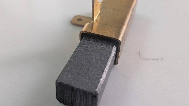 A carbon brush in its brass holder with the spring, removed from a power tool motor