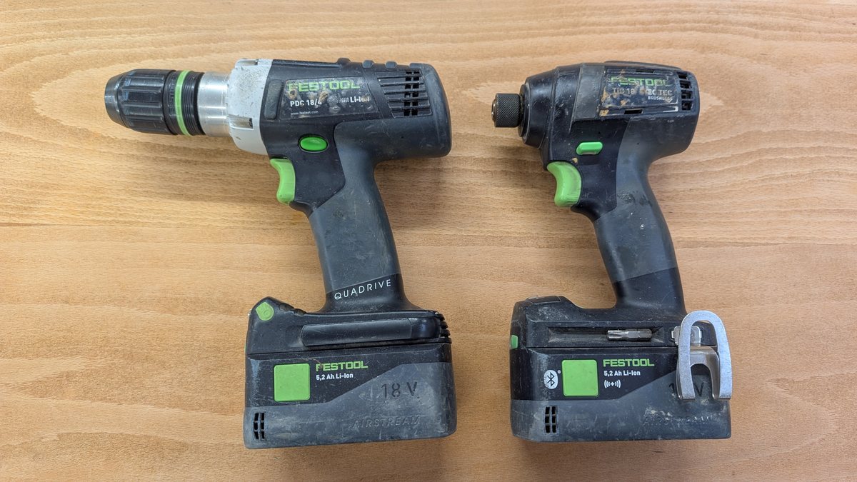 A Festool combi drill and impact driver laid side by side, showing the combi is longer